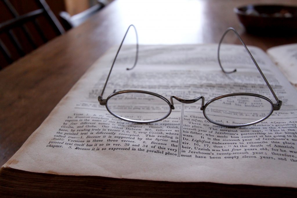 A pair of glasses sits on an open bible on a table.