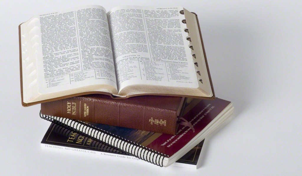 A set of scriptures sits on top of a two manuals. The top book of scriptures is open toward the viewer.